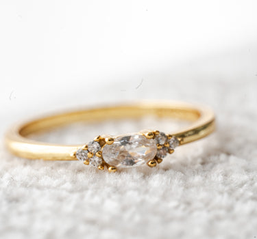 Gold ring with clear gemstones on a textured white surface